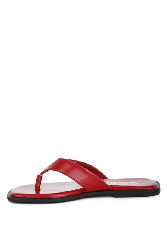 Red toe-post thong flats from the side, showing flat outsole and T-strap