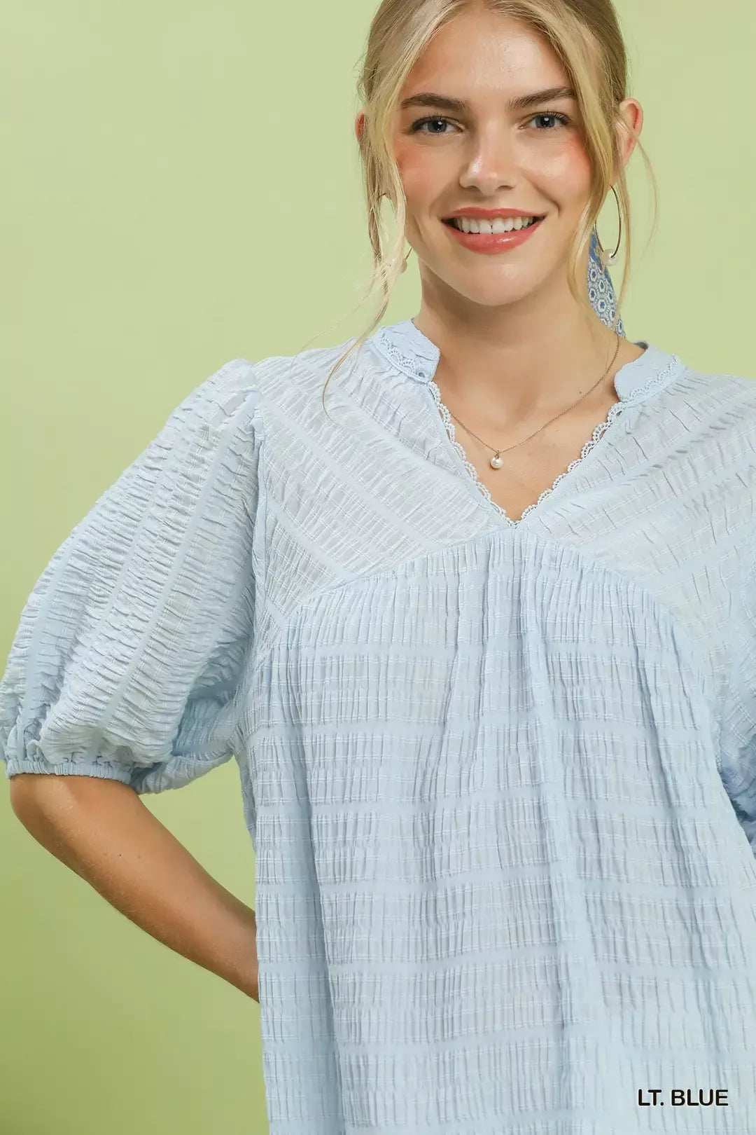 Close-up: light blue V-neck textured blouse with gathered front