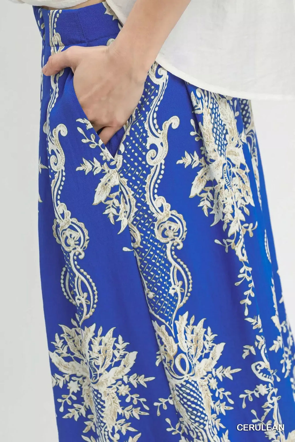 Close-up of blue border print wide-leg pants with cream floral scrolls