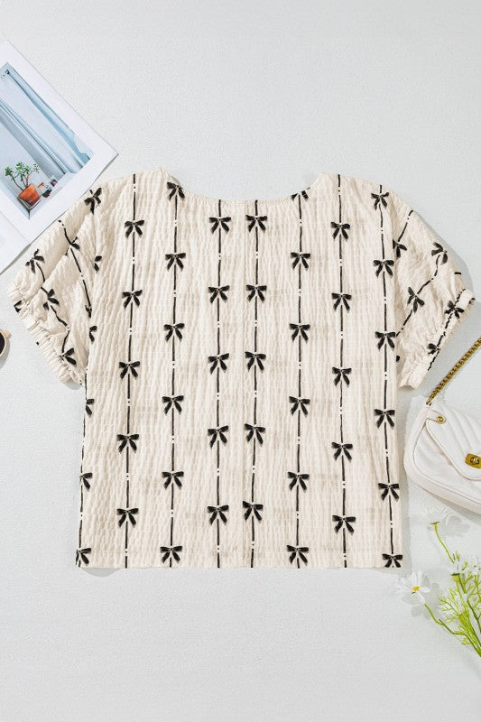 Cream bow-texture top, short puff sleeves, black bow and stripe pattern shown flat