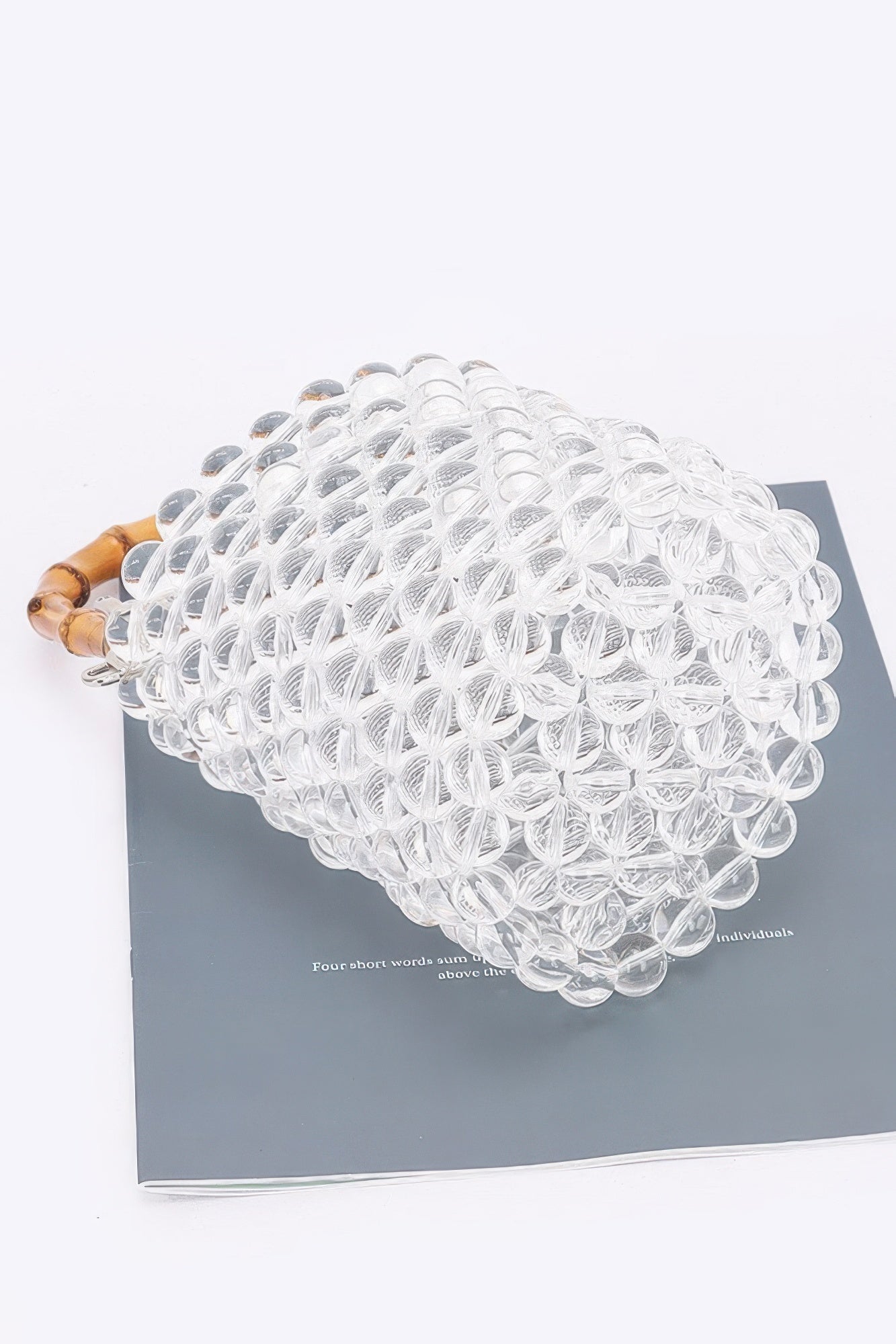 Rounded clear bead tote bag top view with bamboo handle opening and beaded texture