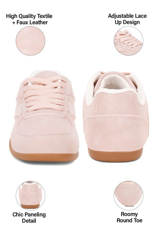Blush-pink lace-up sneakers showing textured textile panels, rounded toe, and thick sole