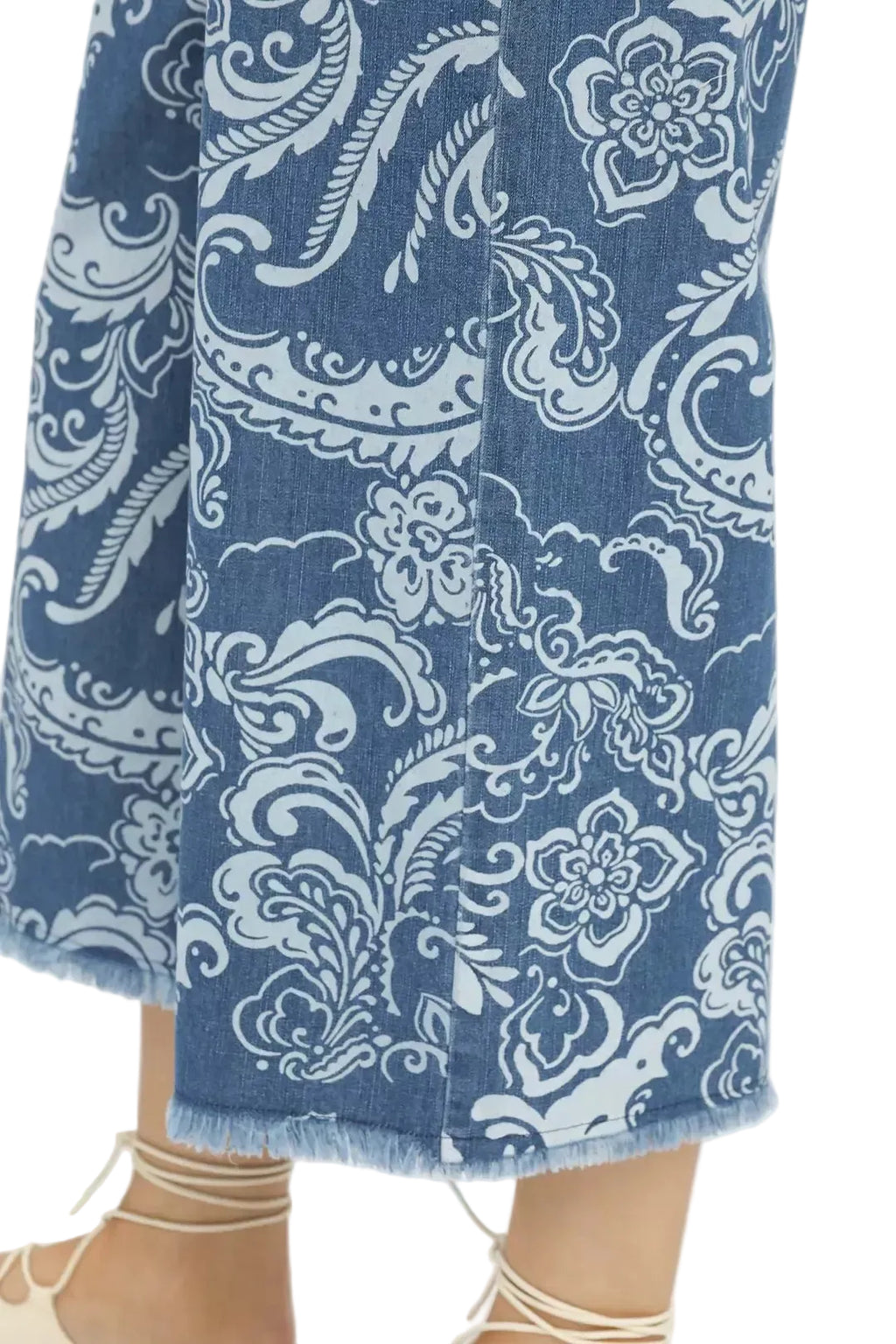 Blue denim crop pants close-up with white paisley print and frayed raw hem