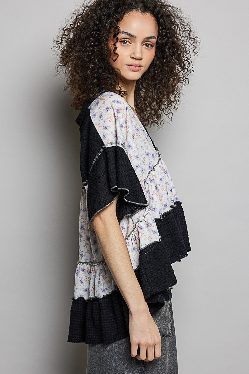 Side view: floral V-neck blouse with black short sleeves and layered ruffle hem