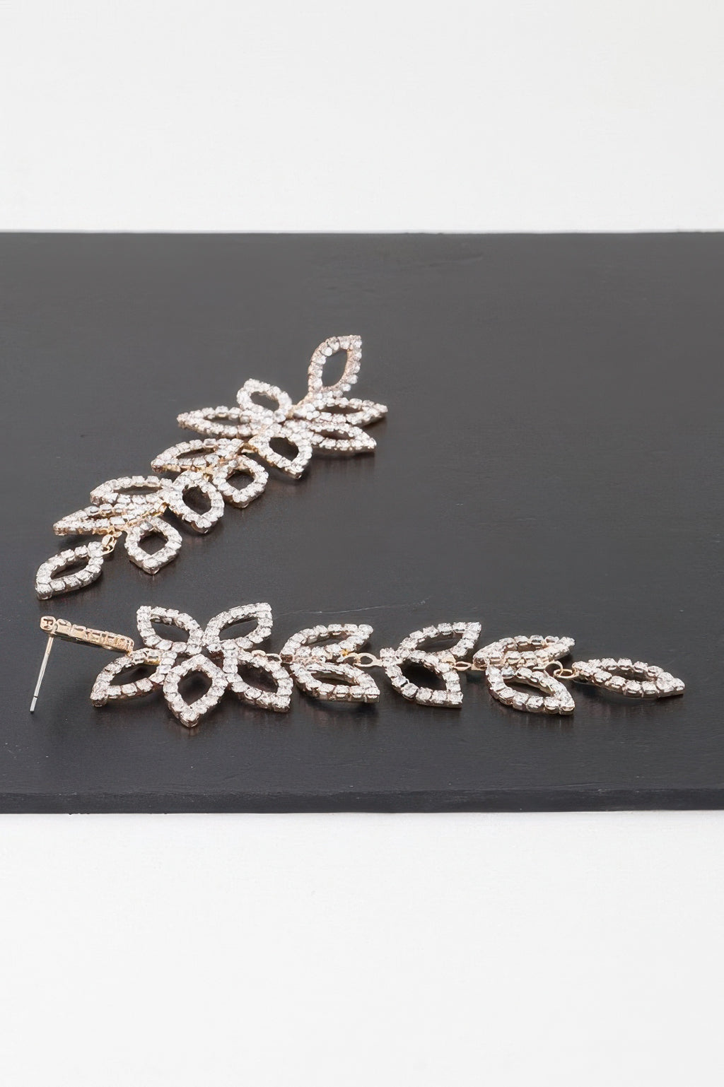 Gold-tone flower petal drop earrings with clear teardrop crystals, laid flat