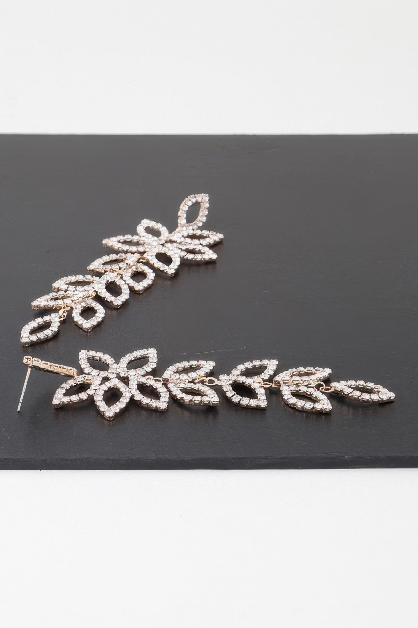 Gold-tone flower petal drop earrings with clear teardrop crystals, laid flat