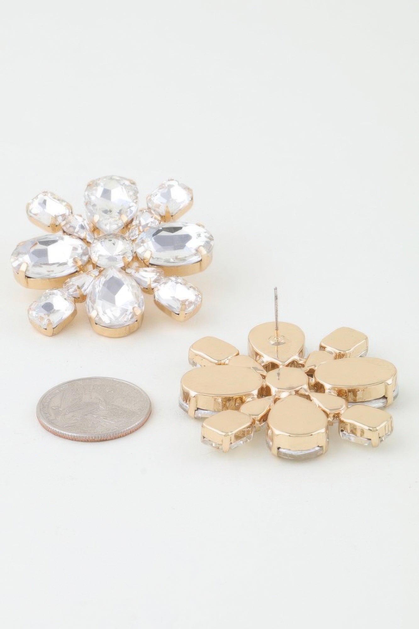Clear flower stud earrings with gold-tone prongs; size coin for scale