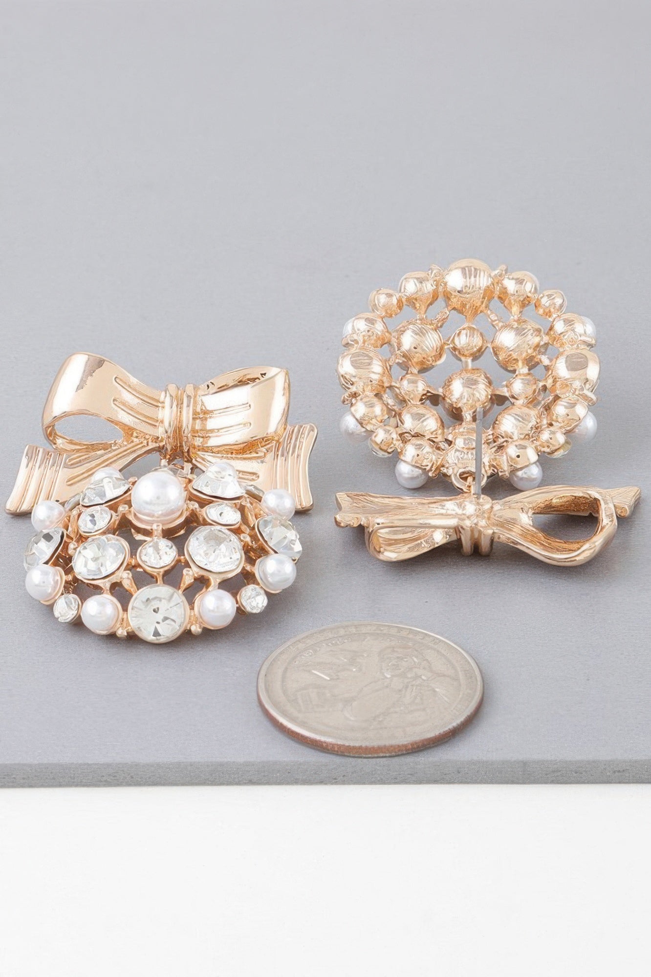 Gold clear ribbon ornament earrings with white crystals, pearls and a bow design