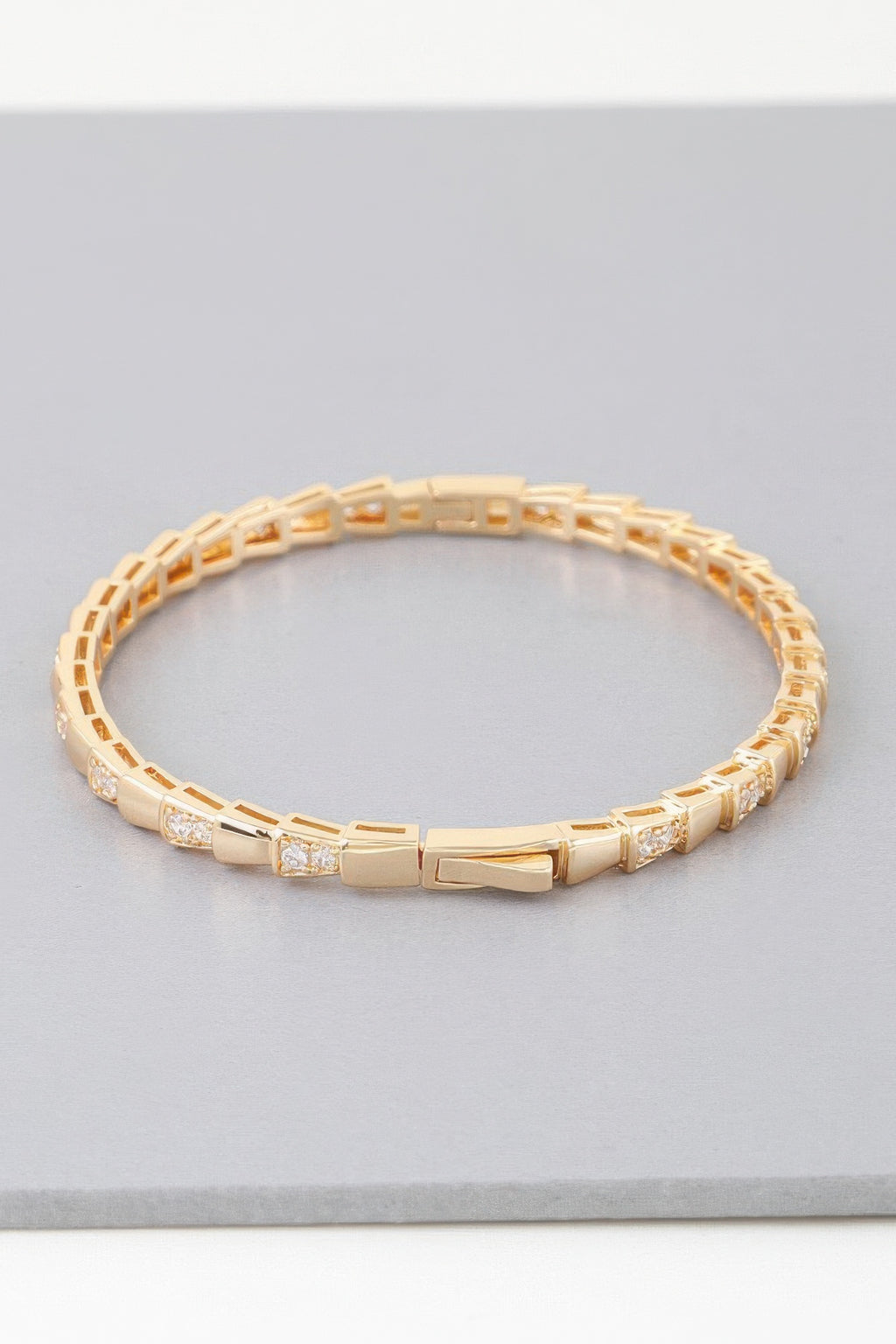 Gold snake-scale bracelet with polished links and tiny clear stone rows at sides