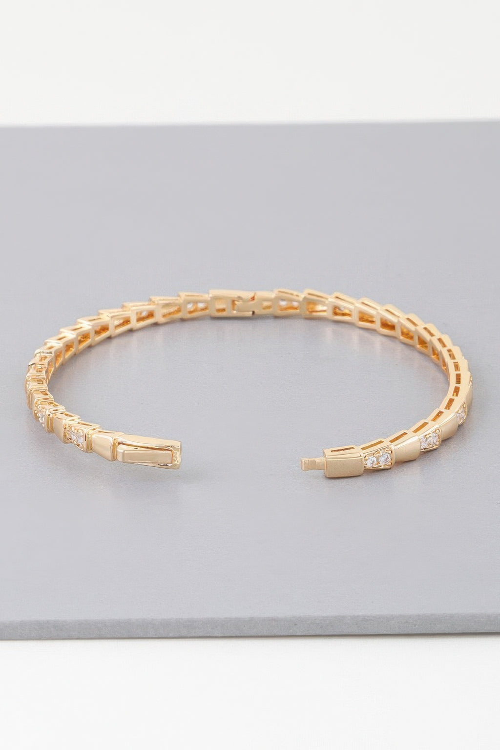Gold snake-scale bangle bracelet with hinged clasp and clear stone details