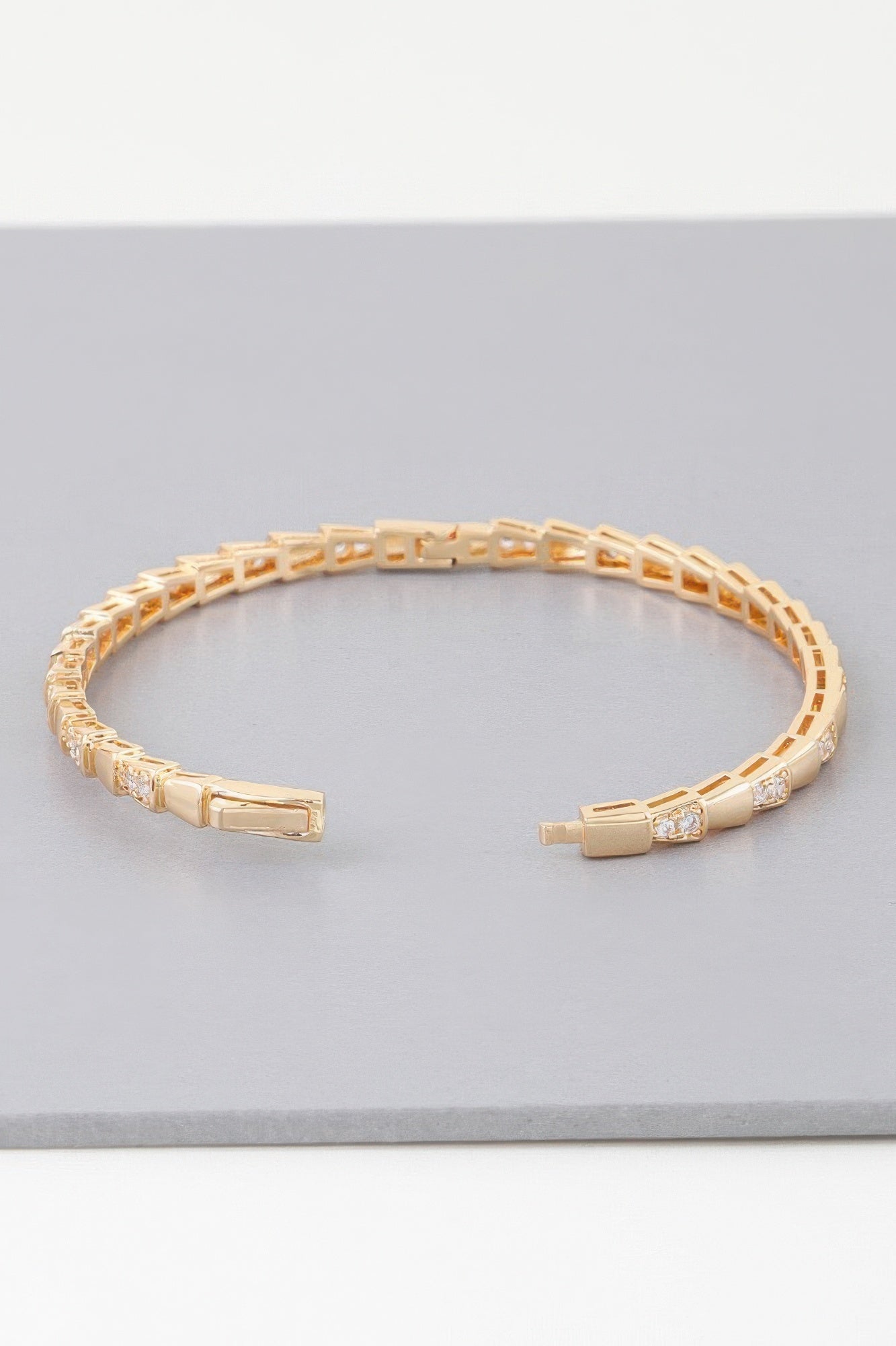 Gold snake-scale bangle bracelet with hinged clasp and clear stone details