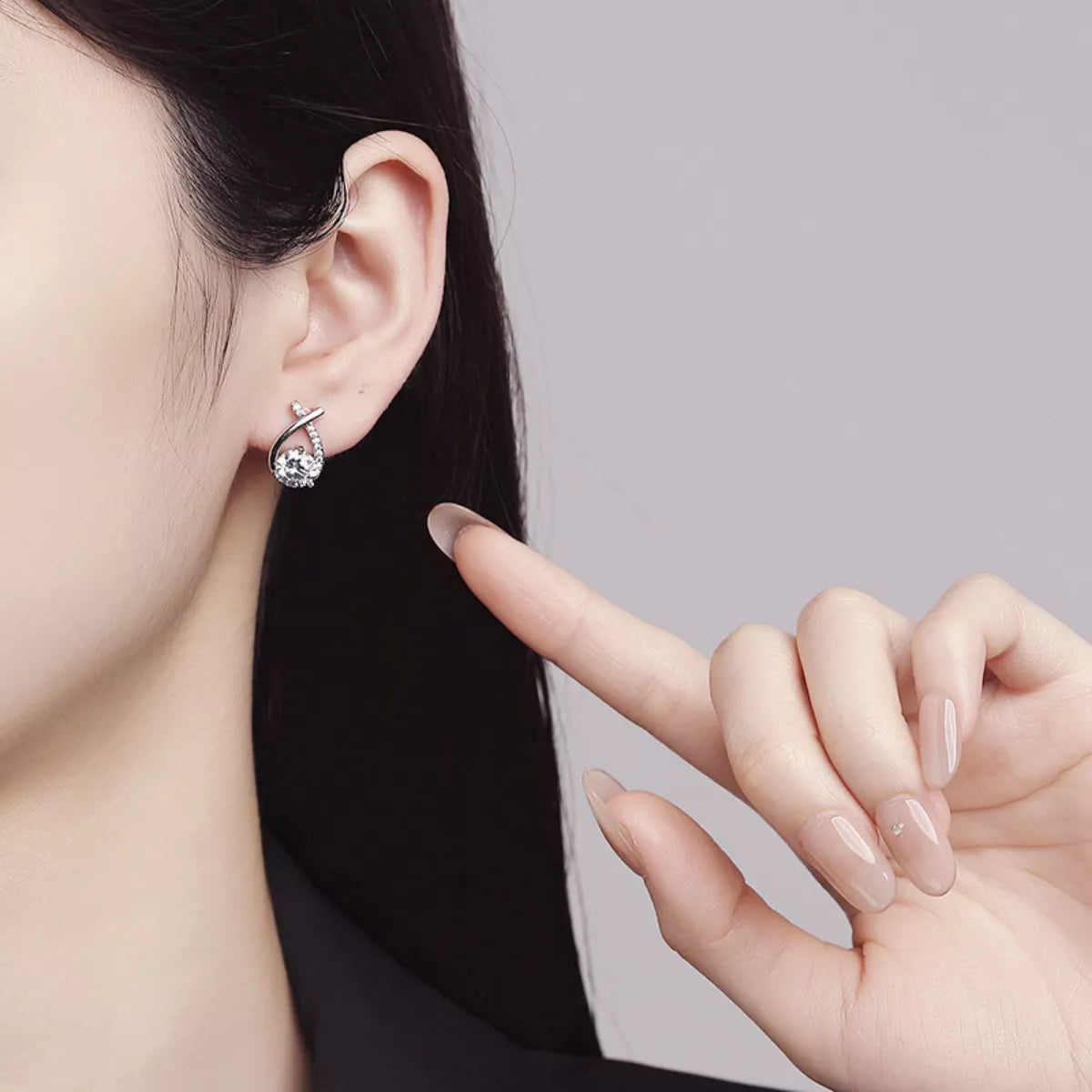 Moissanite teardrop earrings on ear with sterling silver teardrop setting