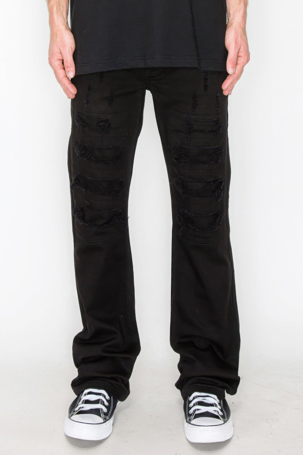 Bootcut jeans in black with large ripped patches and repaired areas at thighs and knees