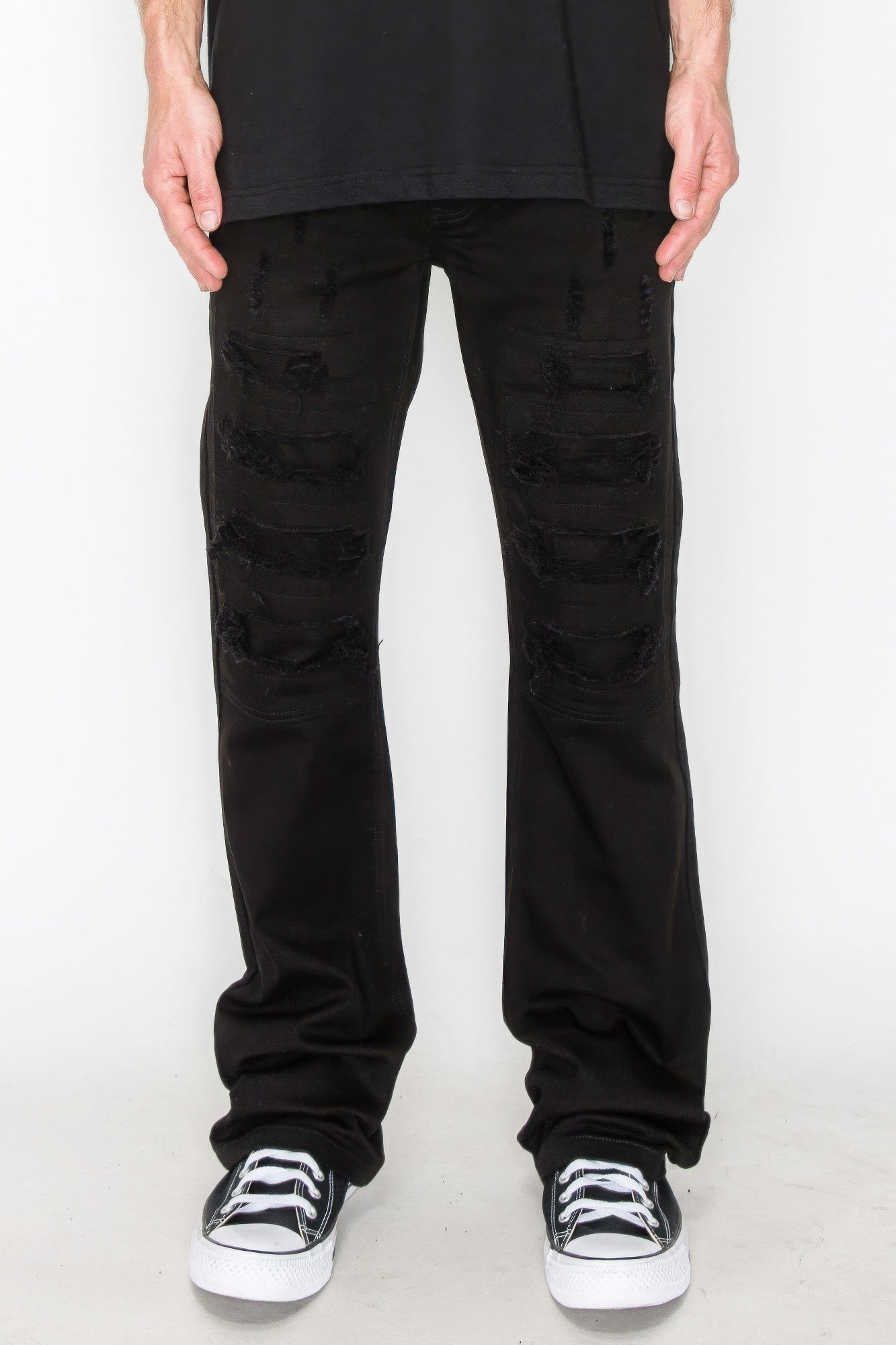 Bootcut jeans in black with large ripped patches and repaired areas at thighs and knees