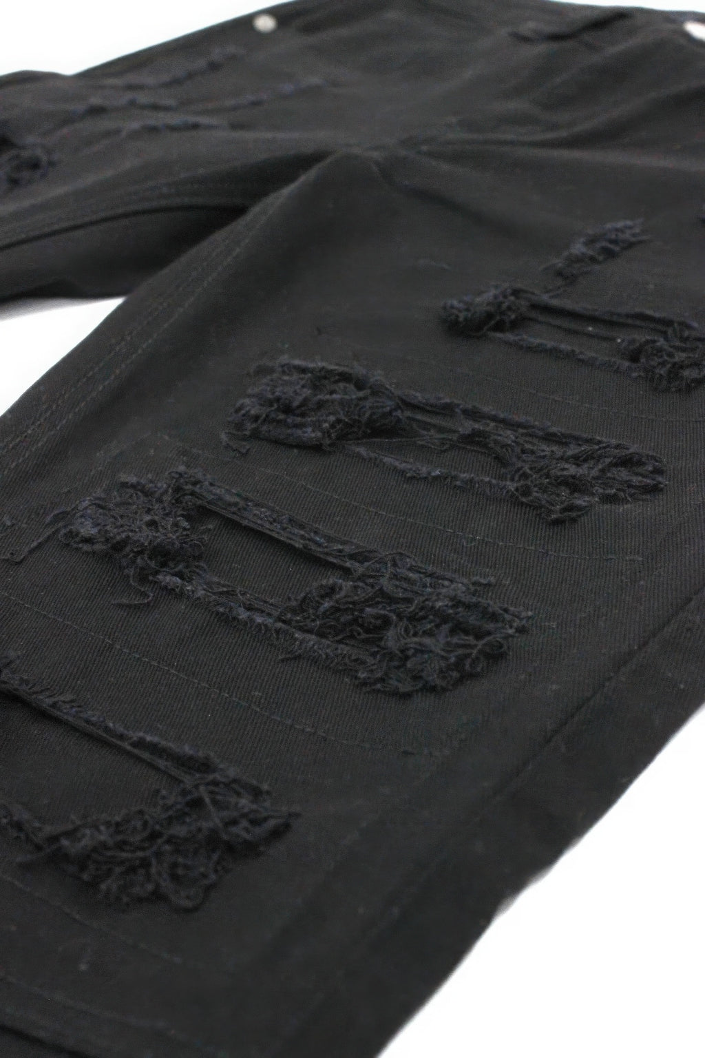 Black denim close-up: torn rips with stitched repair patches