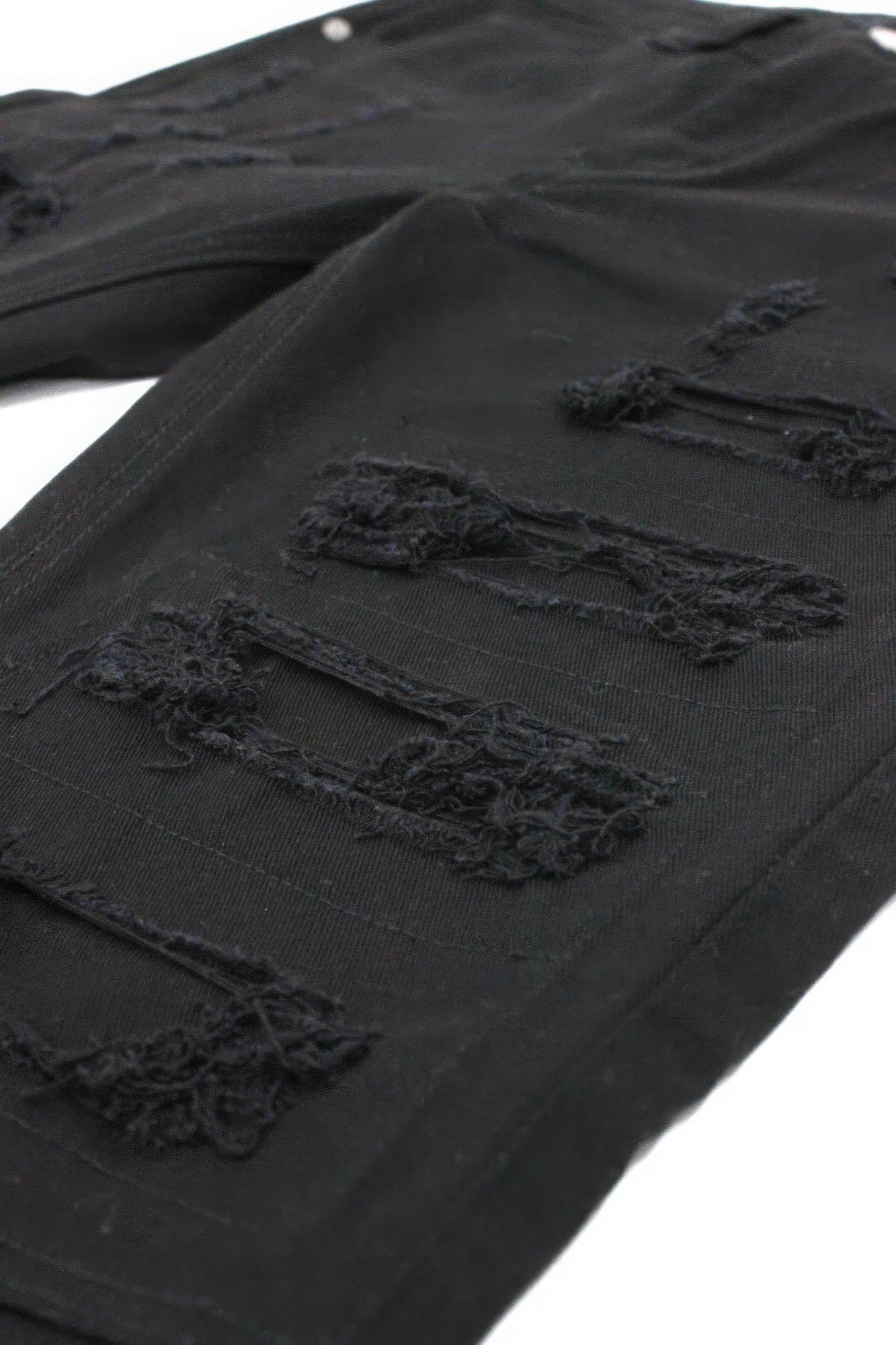 Black denim close-up: torn rips with stitched repair patches