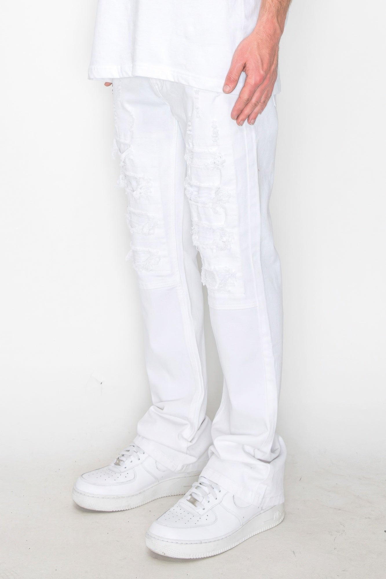 White bootcut jeans with knee rip-repair stitching and panel overlays
