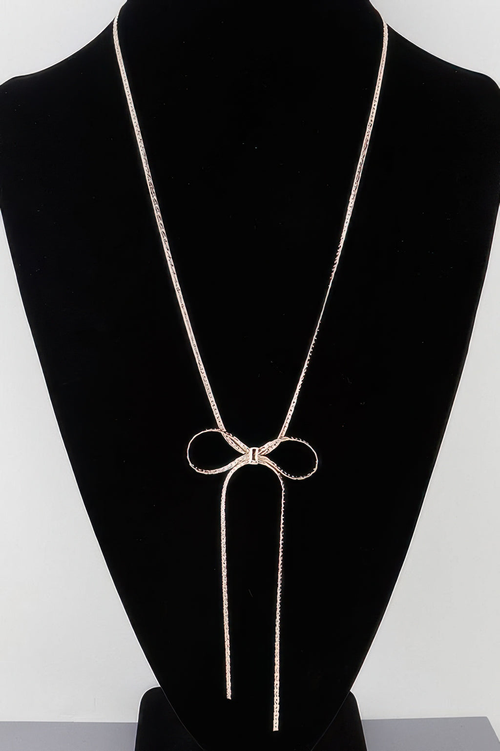Bow necklace with two long tassel chains and a bow pendant, gold-tone