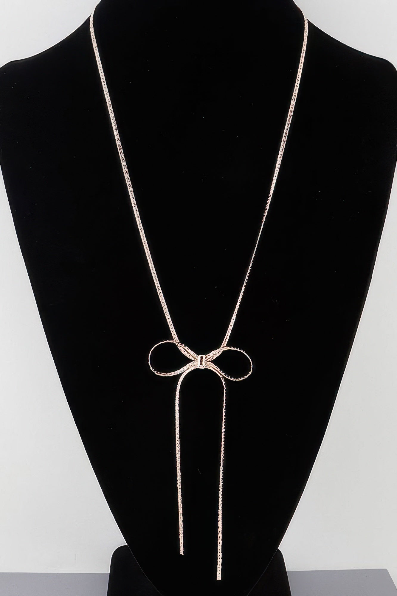 Bow necklace with two long tassel chains and a bow pendant, gold-tone