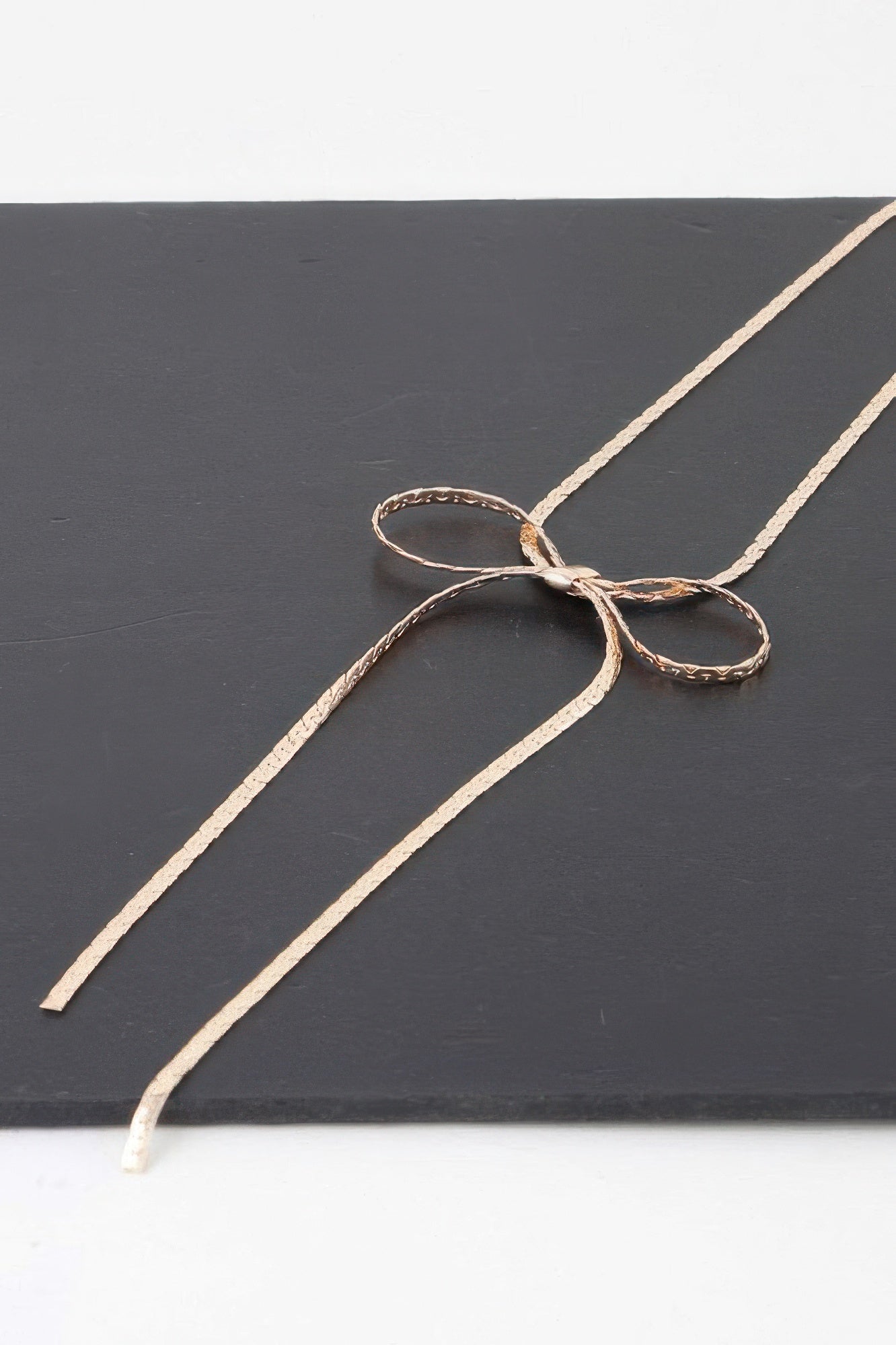 Bow necklace bow pendant with two slim chain tassels, gold-tone close-up