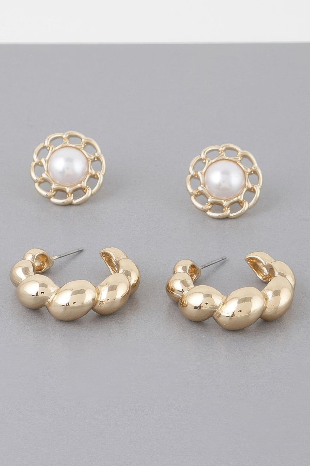 Gold hoop earrings with round white pearl centers and open filigree flower frames