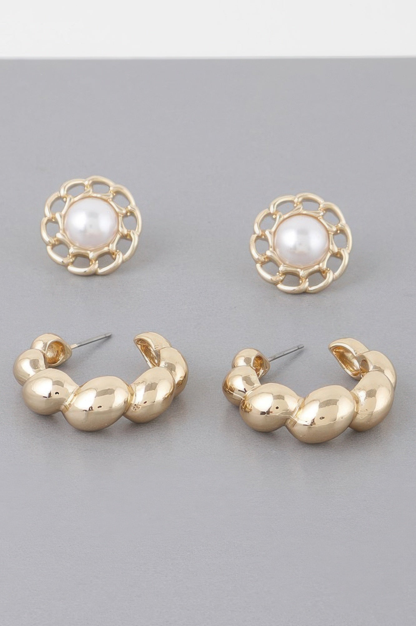 Gold hoop earrings with round white pearl centers and open filigree flower frames
