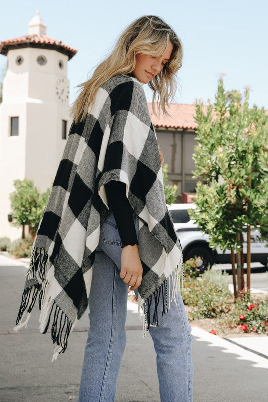 Black-and-white buffalo plaid poncho with fringed edges, worn open-front