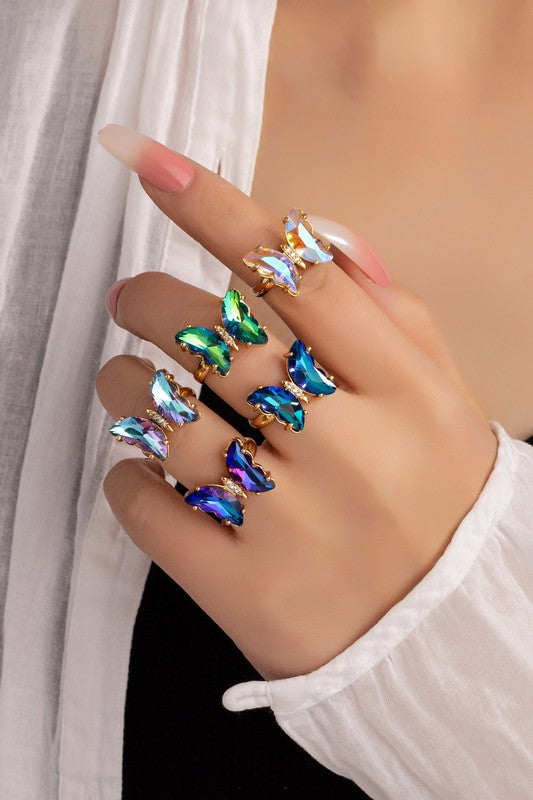 Adjustable brass butterfly ring with teal and green stones on hand, one size