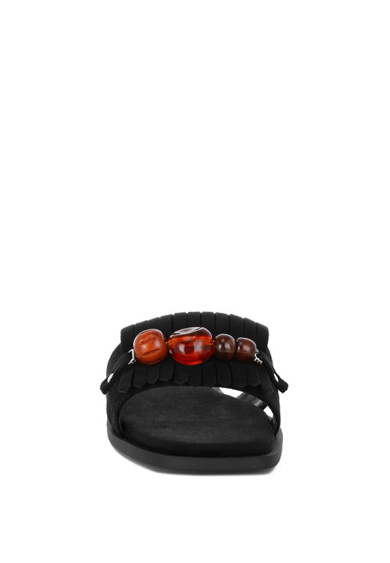 Black slip-on flat sandals with chunky multi-color beaded front and tassel fringe