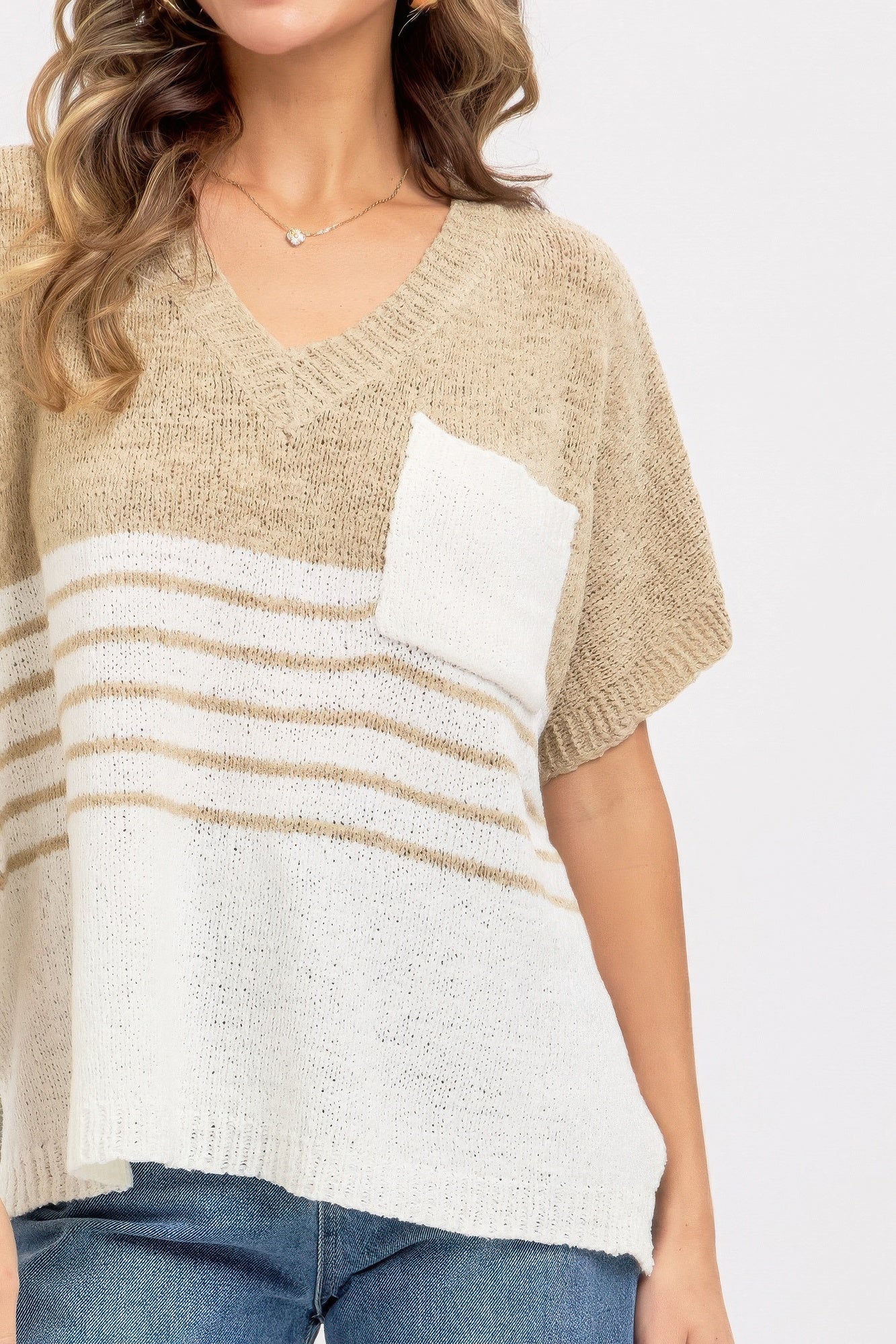 Close-up of taupe knit top: V-neck, short sleeve, white chest pocket and striped band