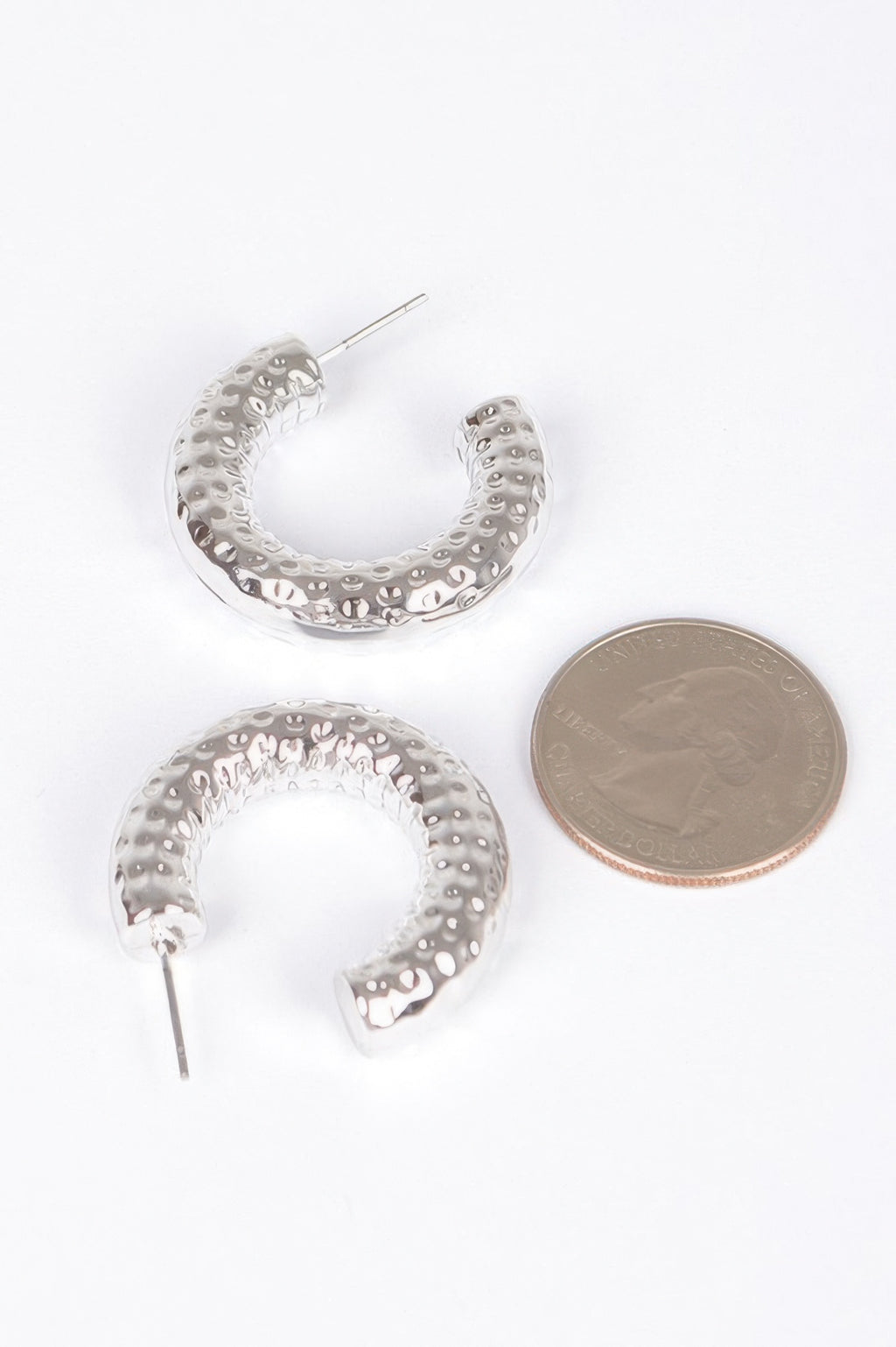 Silver textured hoop earrings with stud posts; size shown with coin comparison