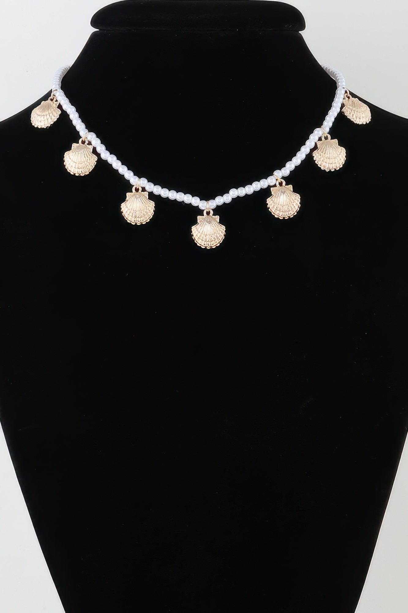 Clamshell charm pearl necklace with gold-toned shell pendants, on display