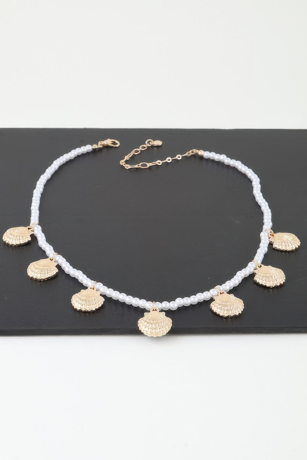 Clamshell charm pearl necklace with white pearl beads, gold shell drop charms, clasp