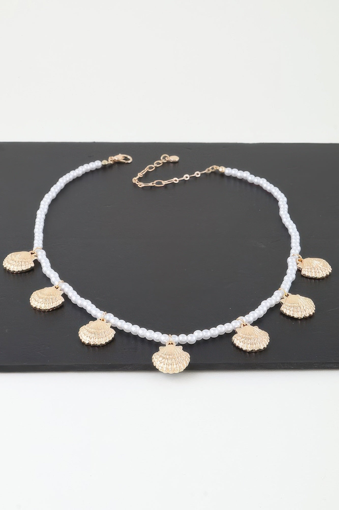 Clamshell charm pearl necklace with white pearl beads, gold shell drop charms, clasp