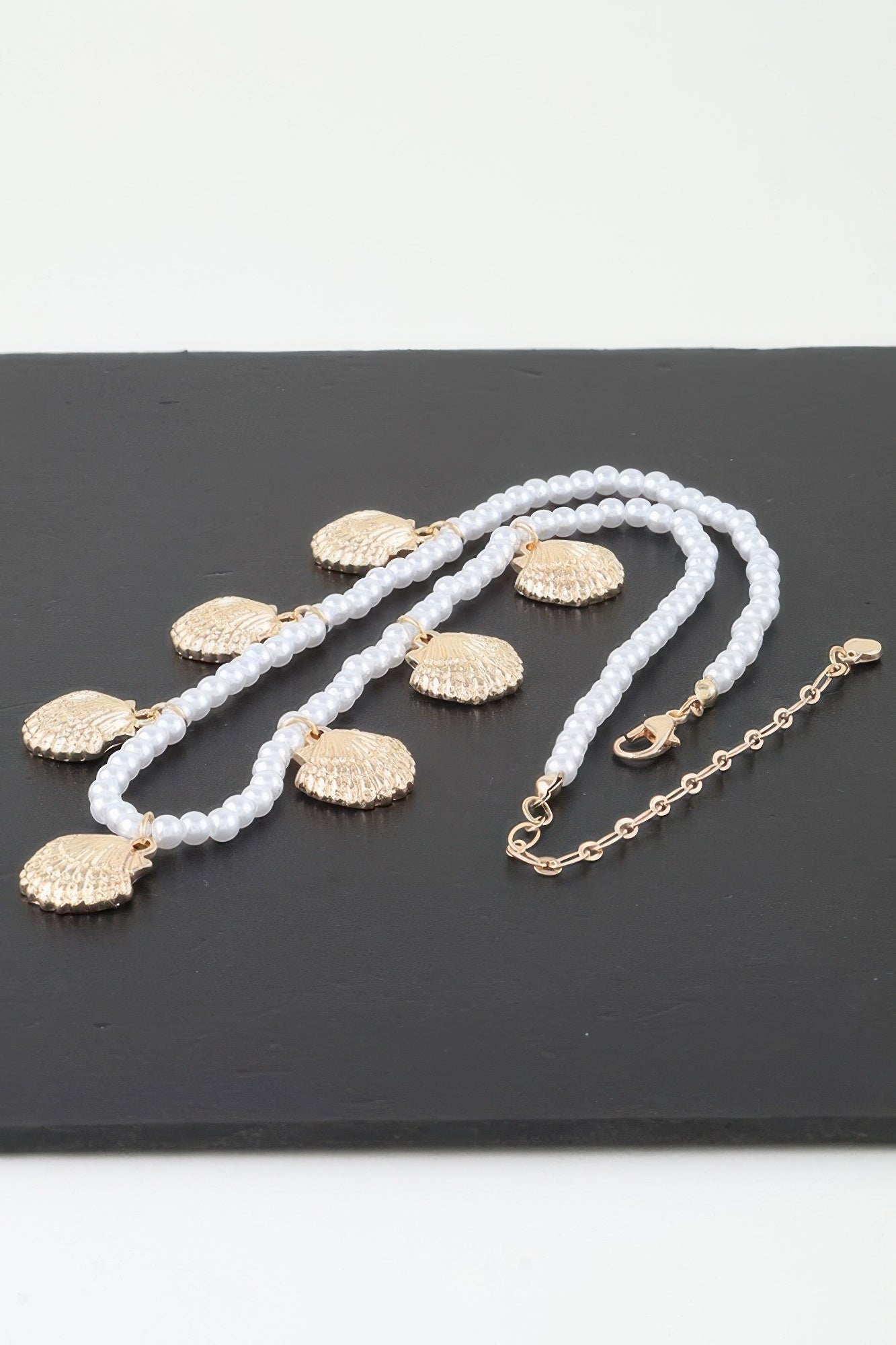 Clamshell charm pearl necklace with white pearl strands and gold-toned shell pendants