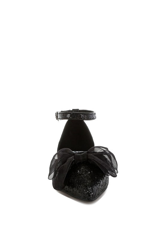 Black glitter pointed-toe flat sandal angled view; sheer bow and ankle strap