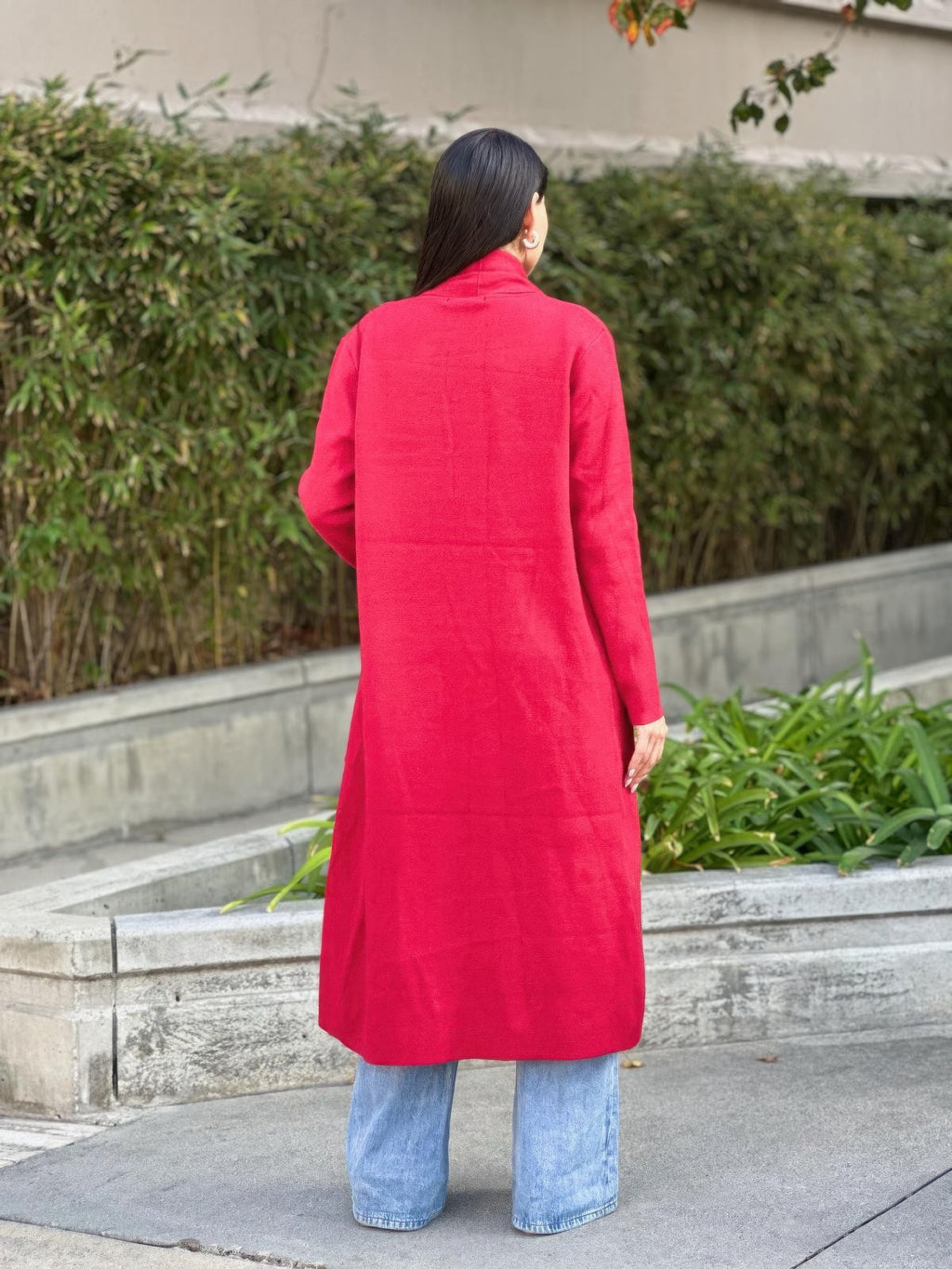 Back of red midi cardigan, fine knit long sleeves, pocket placement visible