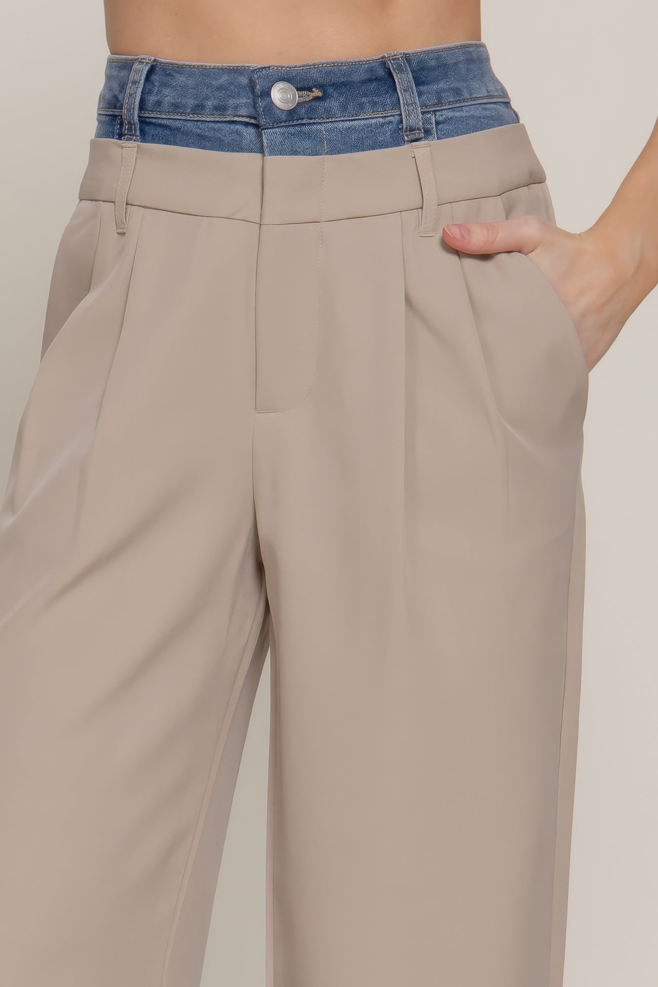 Taupe pants close-up: blue denim waistband, front pleats, side pockets