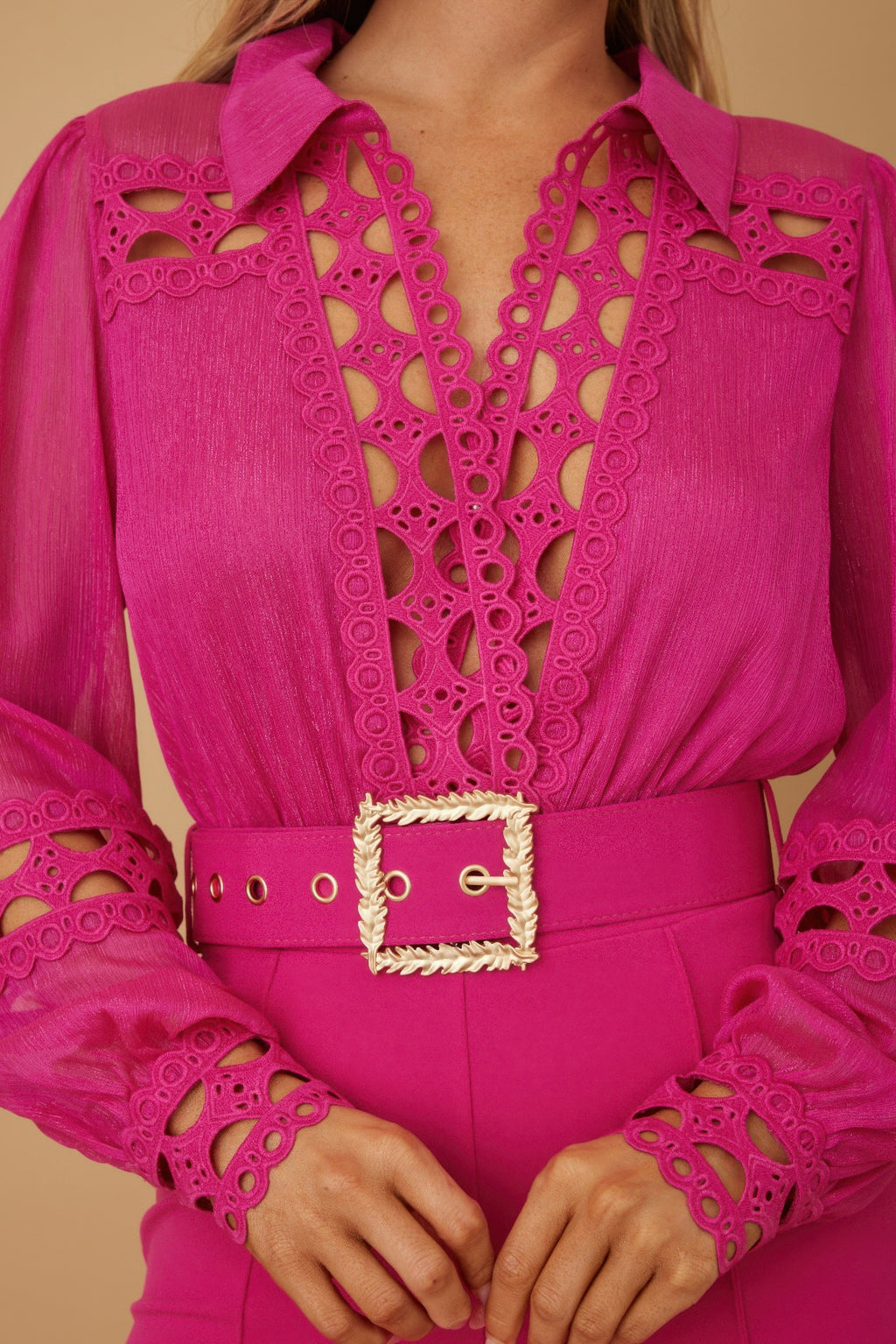 Close-up: fuchsia jumpsuit with crochet cutwork panels and square gold-tone belt