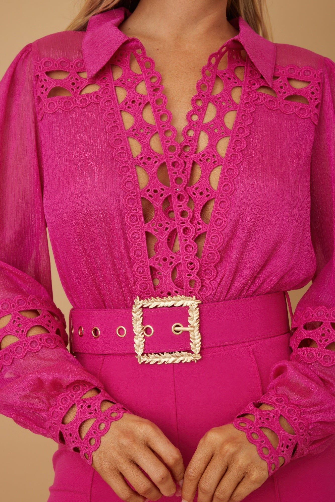 Close-up: fuchsia jumpsuit with crochet cutwork panels and square gold-tone belt