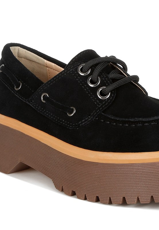 Black suede lace-up loafer close-up with metal grommets and thick platform sole