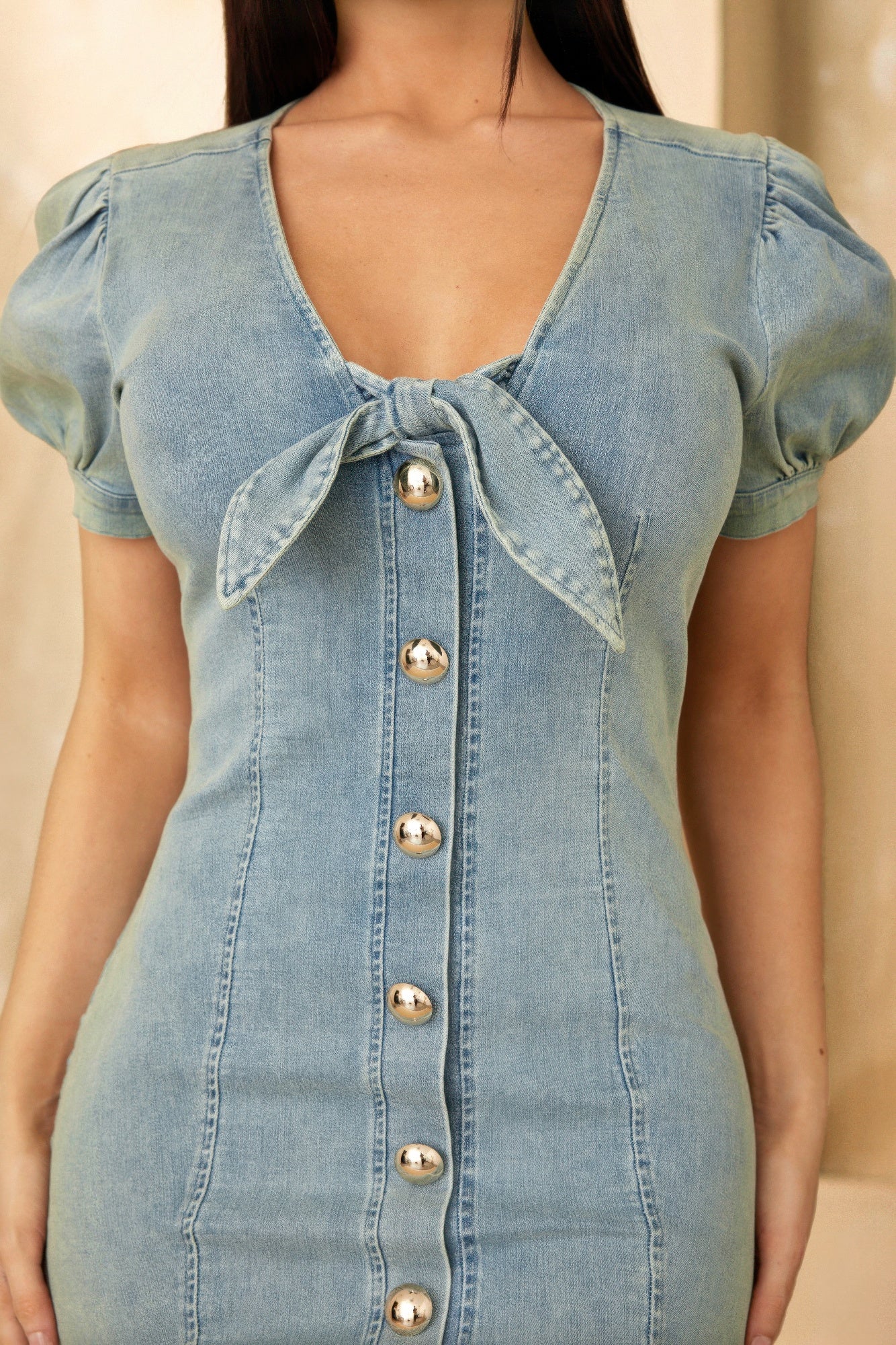 Close-up: denim button-up mini dress with bow tie neckline and gold buttons