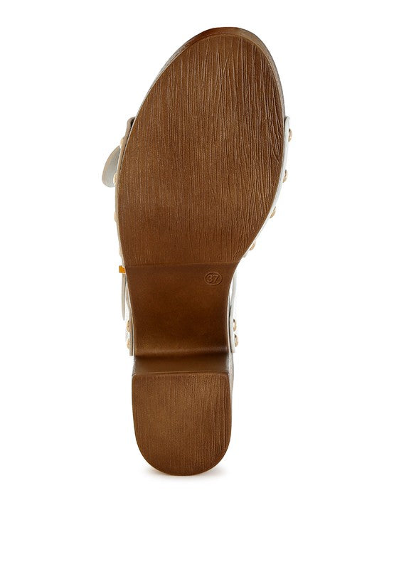 Brown outsole view of white leather clog sandals with platform heel