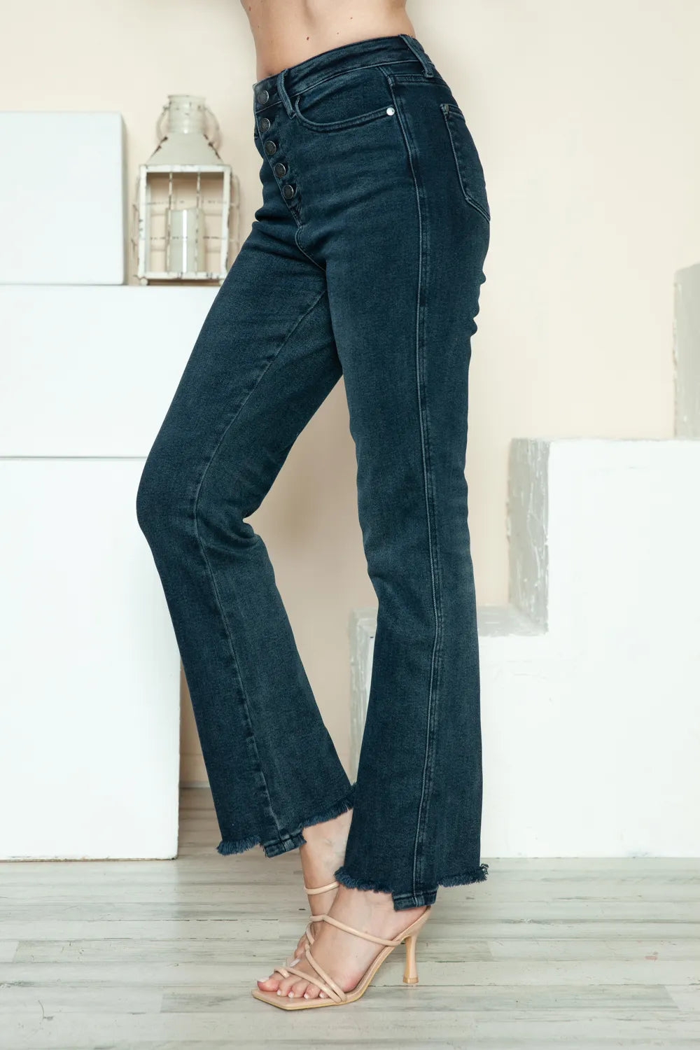 Side view of dark blue straight jeans with raw hem and button-fly closure