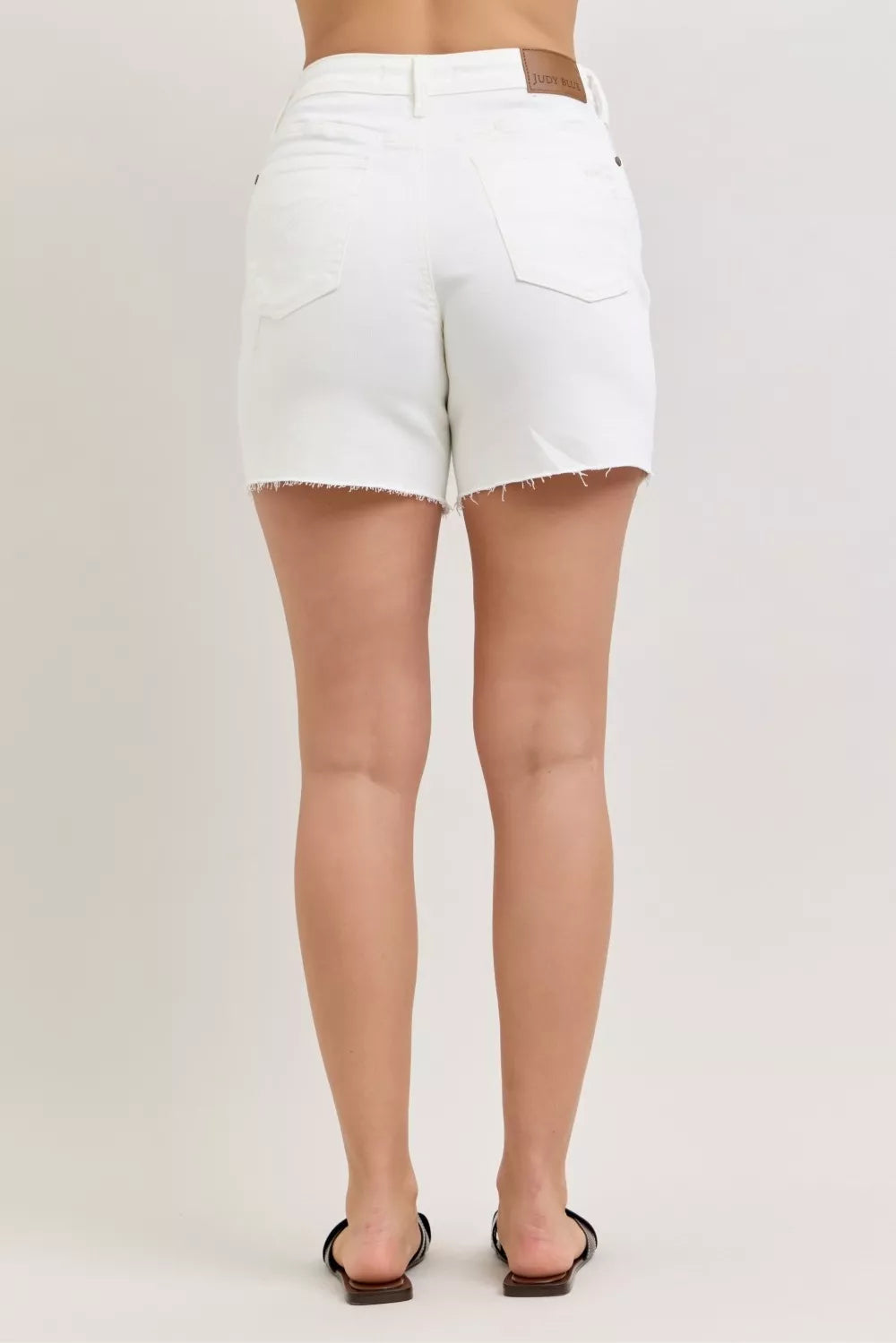 Rear view: high-waist white denim shorts with two back pockets and frayed cutoff hem