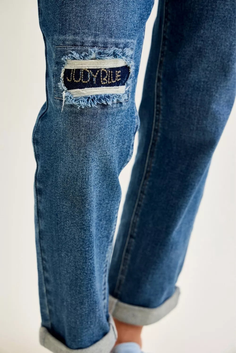 Embroidered repair patch on distressed knee of medium blue Judy Blue jeans