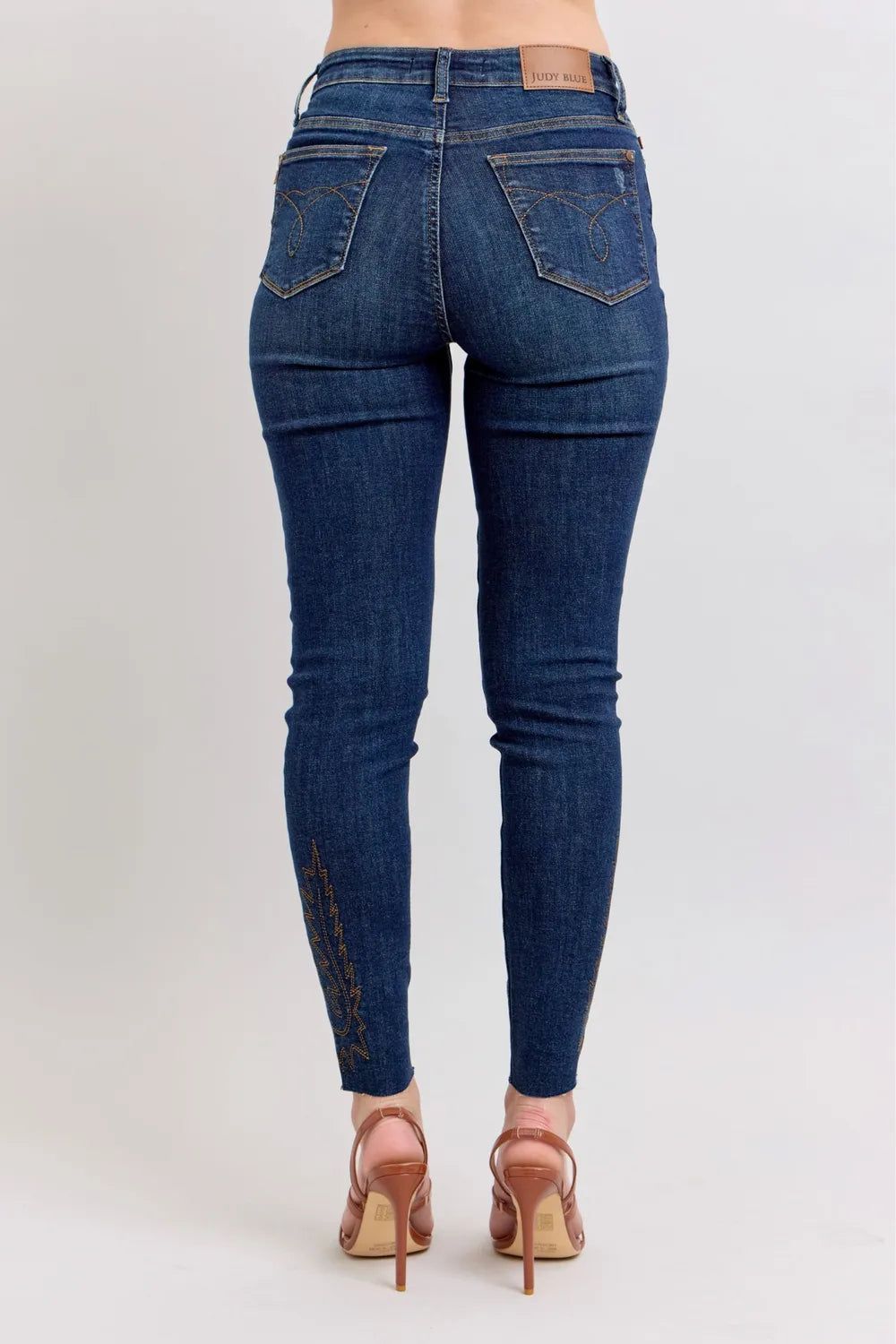 Dark blue high-rise skinny jeans, back view with embroidered accents on legs
