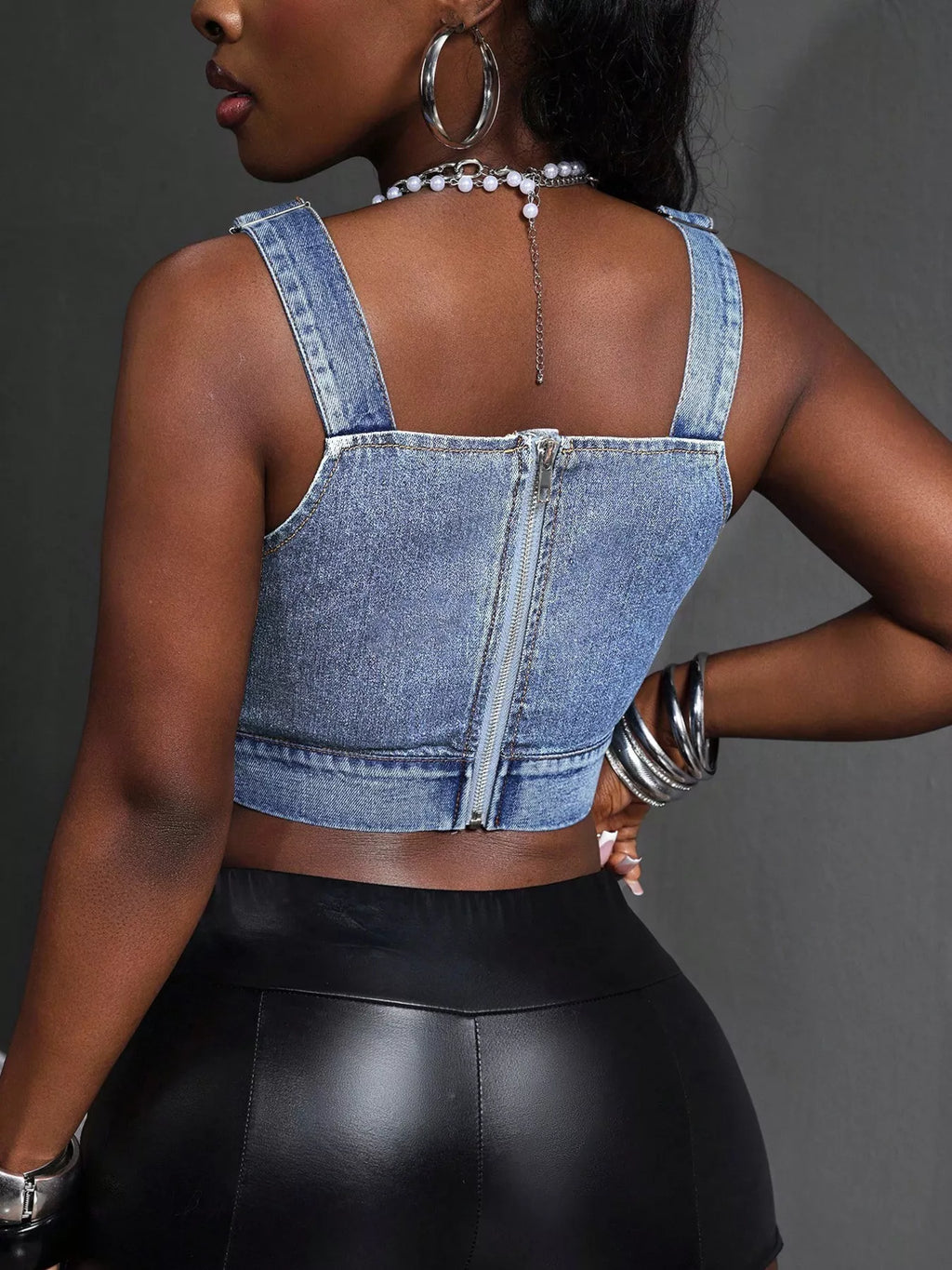 Back view of blue cropped denim top with adjustable shoulder straps and zipper