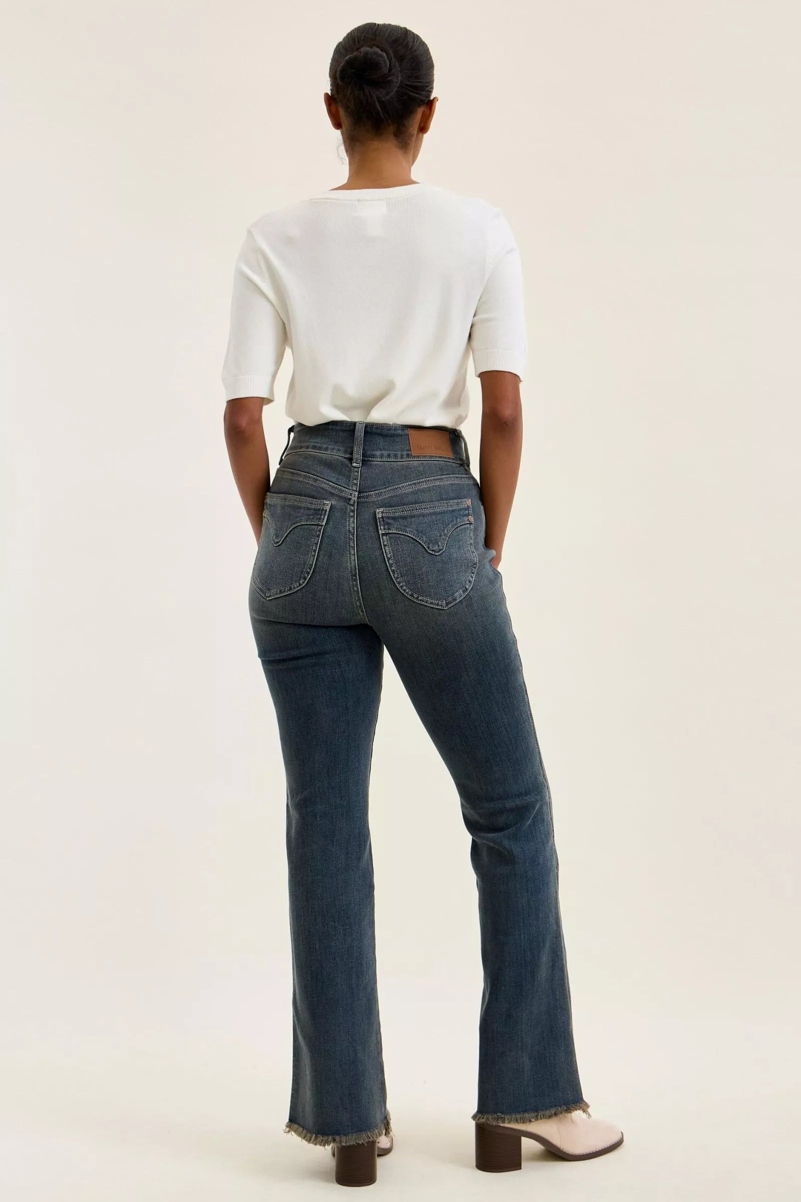 Back view medium-wash high-waist jeans with belt loops and frayed hem