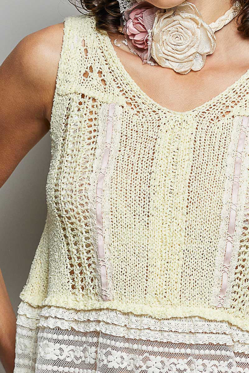 Close-up of lemon V-neck crochet sweater vest with lace detailing at neckline